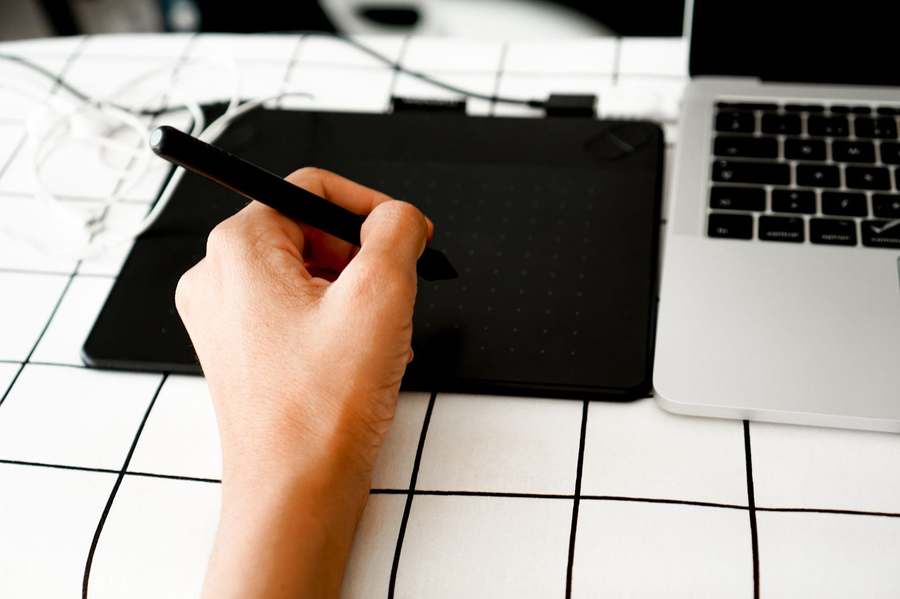 Main utilisant un stylet pour réaliser un travail graphique précis.